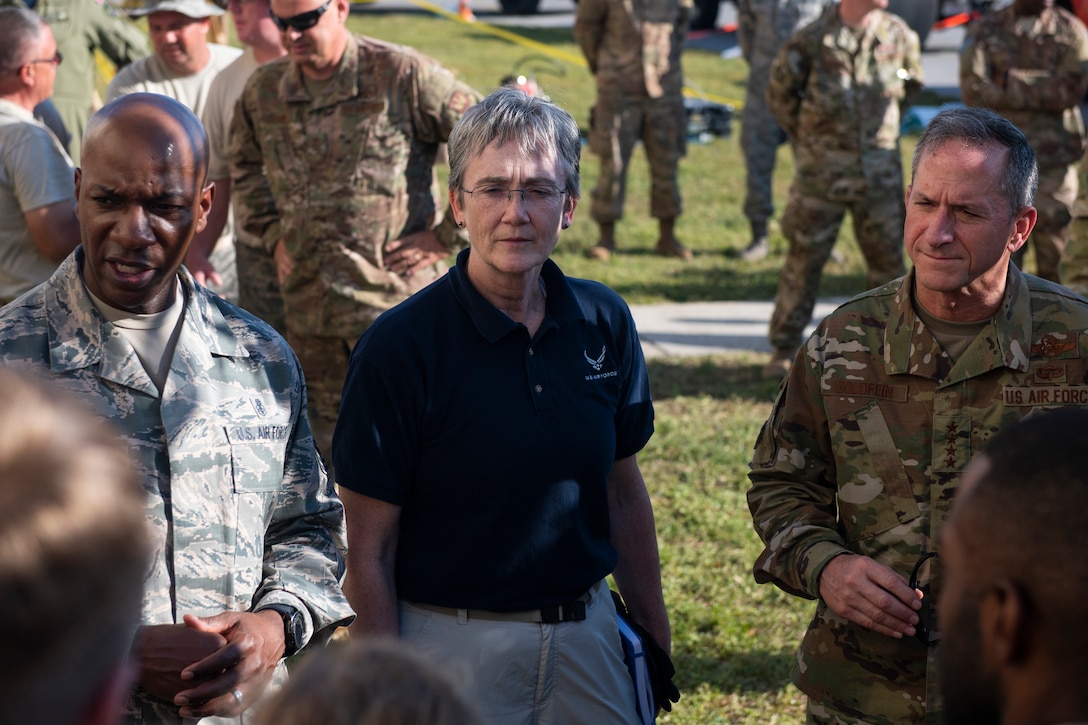 Air Force civilian and military personnel talk with troops outside at a base.