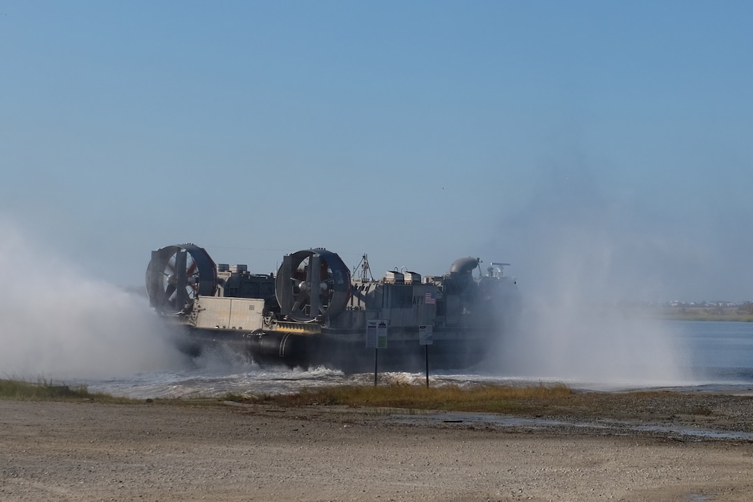 A U.S. Navy Landing Craft Air Cushion flies from Mile Hammock Bay, Camp Lejeune, North Carolina, Oct. 5, 2018 to embark Marines and vehicles to USS New York (LPD 21) during Type Commander Amphibious Training. TCAT allows the 24th Marine Expeditionary Unit, their subordinate units, and the U.S. Navy’s Iwo Jima Amphibious Ready Group to rehearse ship to shore maneuver and expeditionary command and control prior to exercise Trident Juncture 2018. The goal of TCAT is to increase unit and individual proficiency during amphibious operations. The Marines are with 2nd Battalion, 2nd Marines, 24th Marine Expeditionary Unit.  (U.S. Marine Corps photo by Gunnery Sgt. Robert Durham/released)