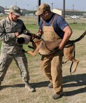 Cadet Royse (left) "catching" a Military Working Dog on a bite sleeve under the supervision of Rene Torres (left), an MWD Breeding Program Training Instructor.