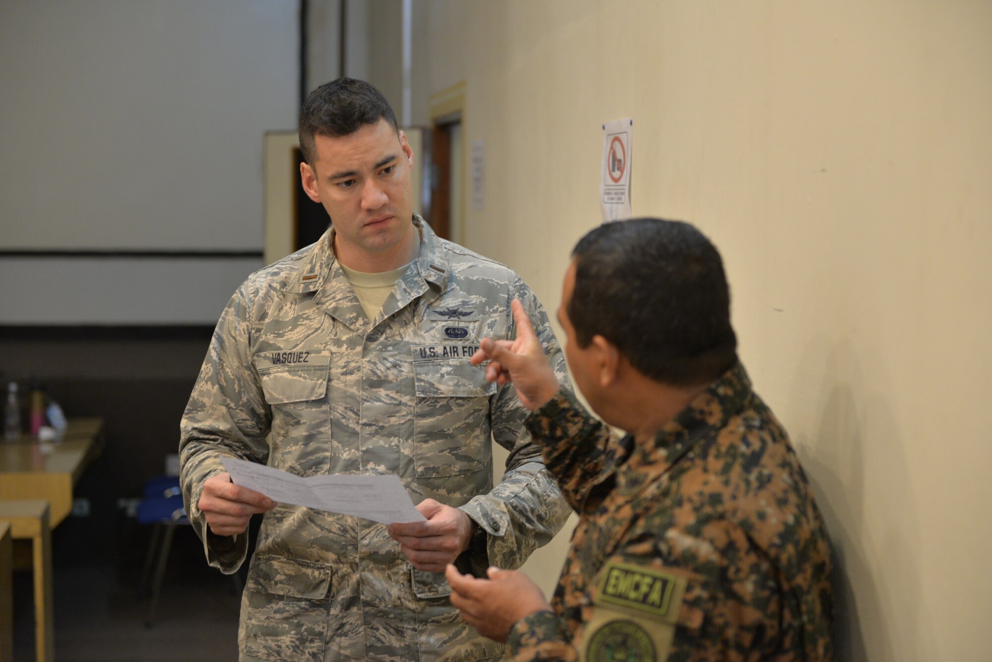 U.S. Air Force 2nd Lt. Darrin Vasquez, an operations officer with the 175th Communications Flight, Maryland Air National Guard and Maj. Javier Campos, Chief Officer of Communications CVI, La Fuerza Armada de El Salvador, discuss the morning schedule, San Salvador, El Salvador, Sept. 27, 2018. Vasquez is part of a multi-state National Guard State Partnership Program, headed by the New Hampshire National Guard, in order to help assess and determine recommendations for the Salvadoran Army as they stand up a cyber security unit. (N.H. Air National Guard photo by Tech. Sgt. Aaron Vezeau)