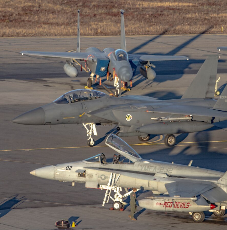 A Republic of Korea Air Force F-15K Slam Eagle fighter aircraft taxis between a U. S. Marine Corps F/A-18C Hornet and a Finnish F-15 Hornet before a familiarization flight during exercise Red Flag-Alaska (RF-A) 19-1 at Eielson Air Force Base, Alaska, Oct. 5, 2018. Red Flag is a series of U.S. Pacific Air Force commander-directed field training exercise for U.S. and coalition forces to provide a realistic joint offensive counter-air, interdiction, close air support and large-force employment training in a simulated combat environment. (U.S. Marine Corps photo illustration by Sergeant Maria A. Noyola)(This photo has been altered for security purposes by blurring the aircraft identification tags)