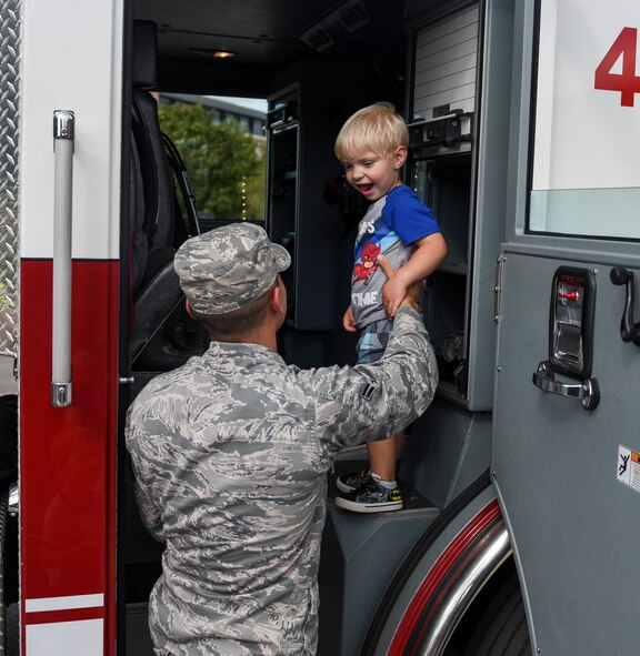 Airman 1st Class Brian Rios, 375th Civil Engineer Squadron firefighter, lifts a child into a fire truck during a visit to the Scott Air Force Base Child Development Center as part of 2018 National Fire Prevention Week, Oct. 9. Throughout the week the fire department visited the Child Development Centers, Scott Elementary School, the Scott Youth Center, hosted a puppet show at the base library, and held an open house and Fall Festival at Fire Station 2 on base. (U.S. Air Force photo by Airman 1st Class Chad Gorecki)