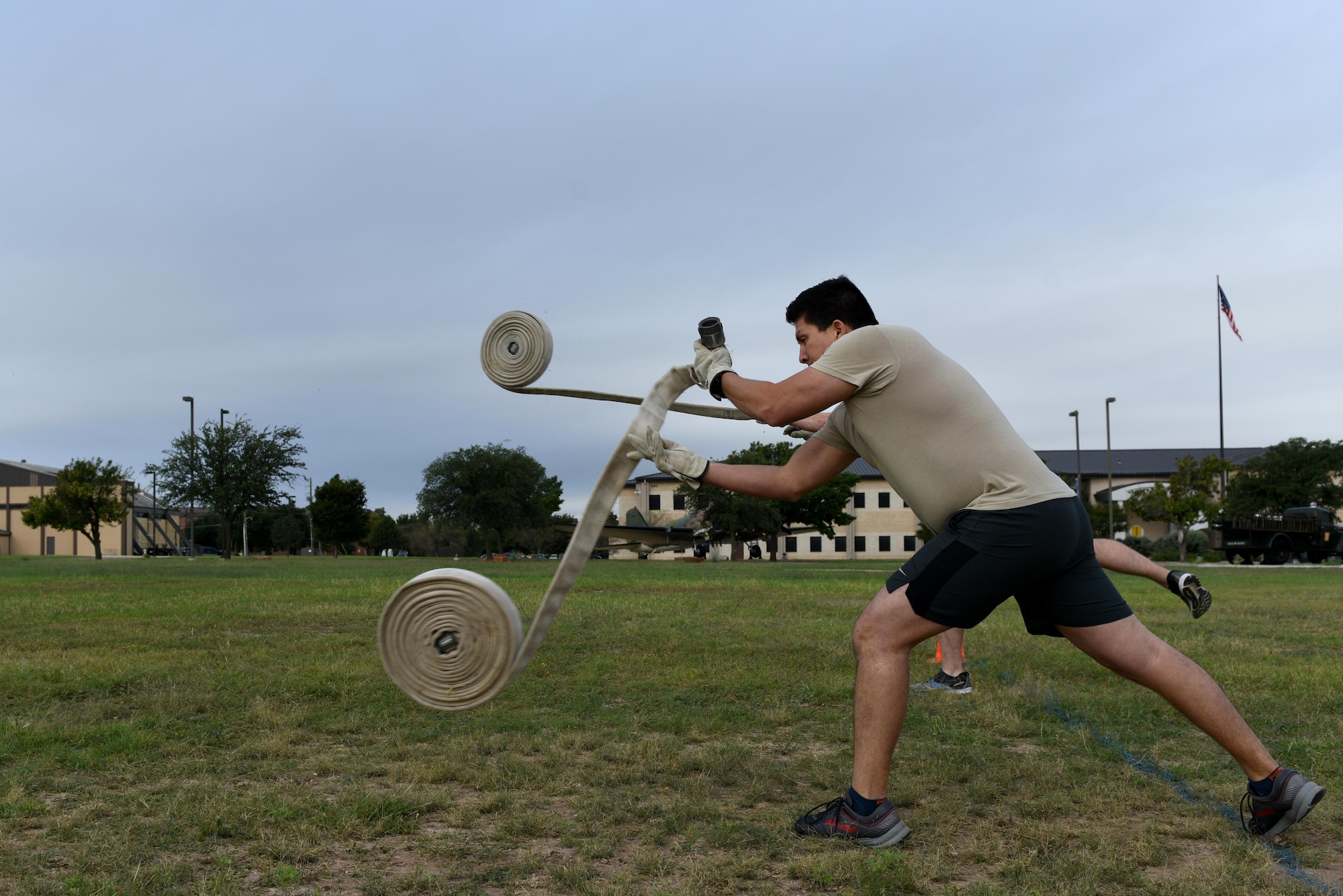 U.S. Air Force Staff Sgt. Cesar Huerta rolls out a fire hose during the 13th Annual Fire Muster on Goodfellow Air Force Base, Texas, Oct. 12, 2018. Once Huerta rolled out the 100-foot hose, team members had to reroll the hose. (U.S. Air Force photo by Senior Airman Randall Moose/Released)