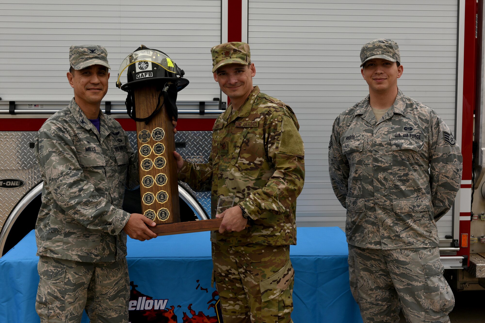 U.S. Air Force Col. Ricky Mills, 17th Training Wing commander, presents the Fire Muster Trophy to Maj. Paul Gesl, 17th TRW staff judge advocate, and Staff Sgt. Cesar Huerta, 17th TRW paralegal during the 13th Annual Fire Muster on Goodfellow Air Force Base, Texas, Oct. 12, 2018. With a time of 5 minutes, 56 seconds, this year marks the 17th Training Wing judge advocate’s seventh win out of the 13 events. (U.S. Air Force photo by Senior Airman Randall Moose/Released)