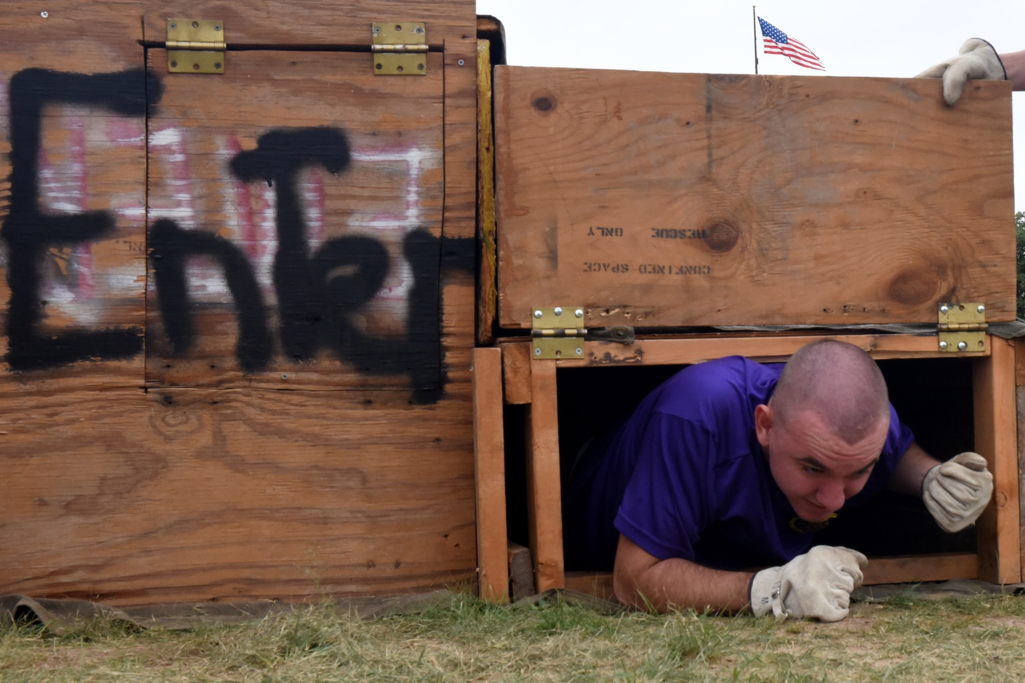 U.S. Air Force Senior Airman Randall Moose, 17th Training Wing Public Affairs photojournalist, exits an obstacle during the 13th Annual Fire Muster on Goodfellow Air Force Base, Texas, Oct. 12, 2018. Moose had to enter through the left side of the confined space trainer and traverse a series of beams in darkness to exit out the other side. (U.S. Air Force photo by 2nd Lt. Matthew Stott/Released)