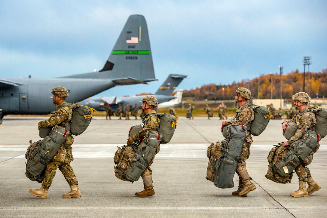 Paratroopers line up outside Air Force aircraft with all their gear.