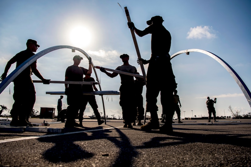 Airmen work together to build a frame for a shelter.