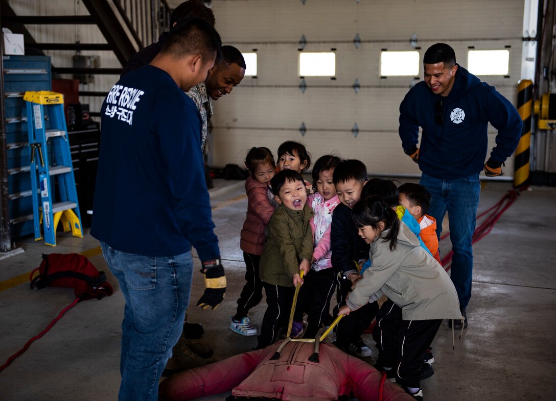 Students from Su Song Elementary School tug on a practice dummy at an open house at Kunsan Air Base, Republic of Korea, Oct. 11, 2018. Fire fighters often use training dummies to practice carrying someone who is unconscious or unable to walk to safety. (U.S. Air Force photo by Senior Airman Stefan Alvarez)