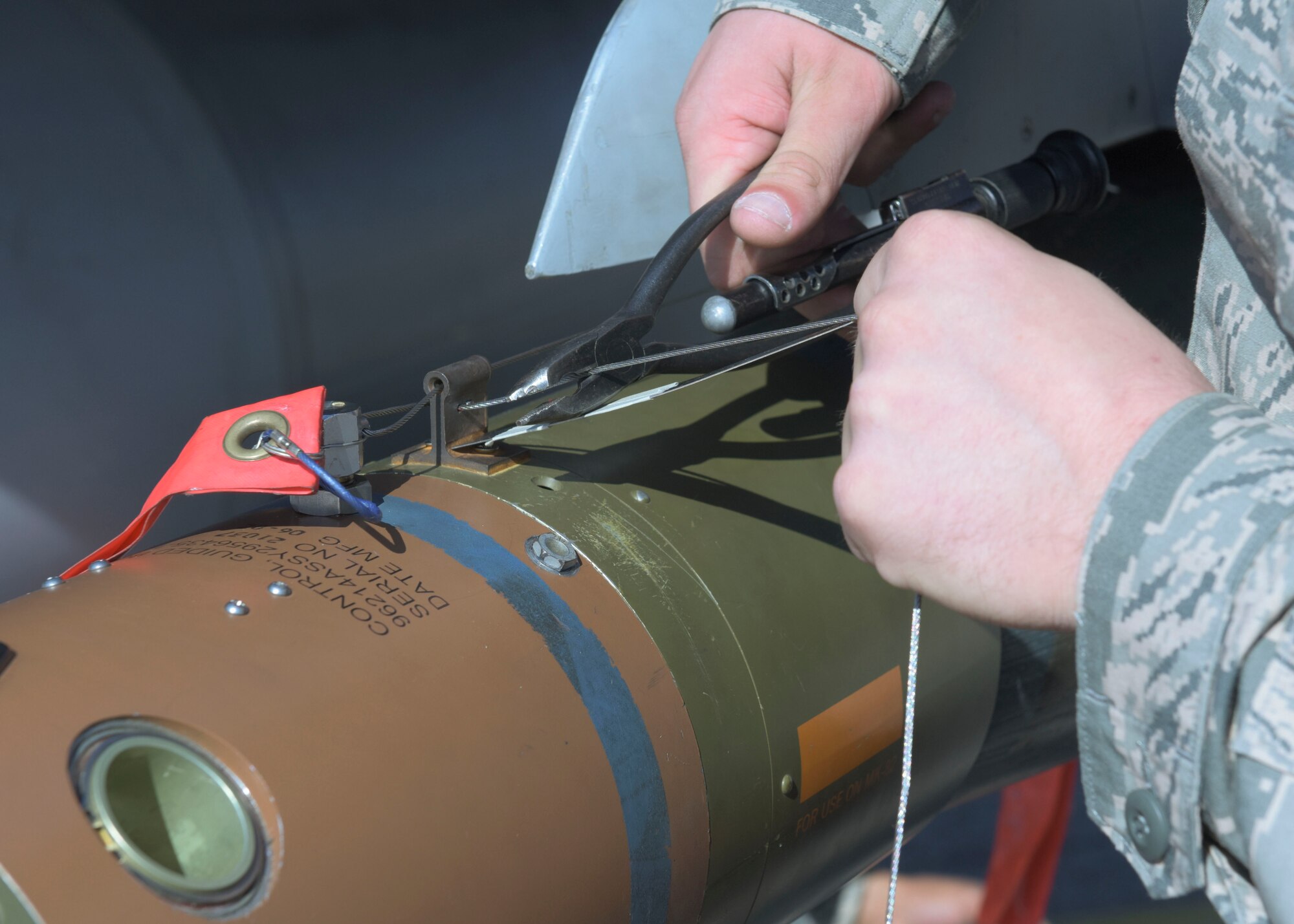 U.S. Air Force Senior Airman Zachary Bosley, a weapons load crew member with the 51st Aircraft Maintenance Squadron, cuts an arming lanyard during a load crew competition on Osan Air Base, Oct. 12, 2018. Precision is necessary during load crew competitions and real-world loads as a mismeasurement can cause a munition to trigger too early, too late or not at all. (U.S. Air Force photo by Staff Sgt. Timothy Dischinat)