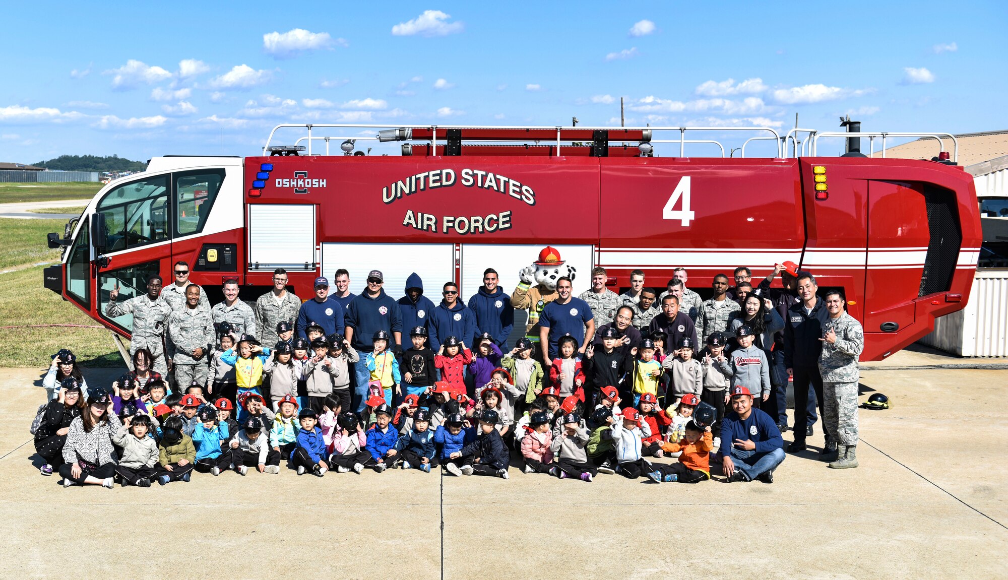 Members of the 8th Civil Engineering Squadron fire department, students and staff from Su Song Elementary School pose for a picture at Kunsan air Base, Republic of Korea, Oct. 11, 2018. The Kunsan Fire Department welcomed 60 students from a local school to show them the equipment they use and teach them about fire safety. (U.S. Air Force photo by Senior Airman Stefan Alvarez)