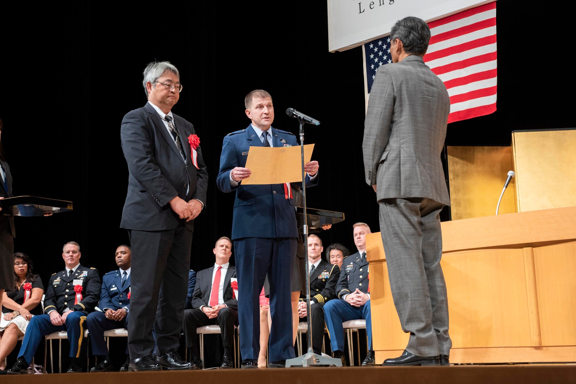 Koutarou Yoshida, North Kanto Defense Bureau director general, left, and Col. Dominic A. Setka, 5th Air Force chief of staff, right, present the award for 30 years of service to Hiraku Suzuki, 374th Civil Engineer Squadron painter foreman-B, during the USFJ Length-of-Service Awards Ceremony at the Yutorogi Hall in Hamura City, Japan, Oct. 10, 2018.