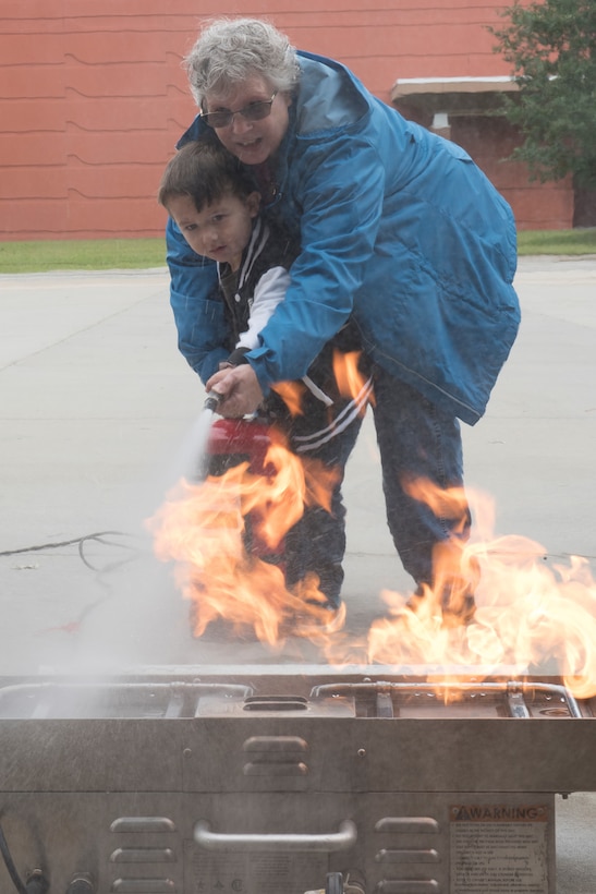 John Henry Yohn, age 3, son of Brian Yohn, Fort Eustis Fire and Emergency Services firefighter, and his grandmother, Sheryl Yohn, put out a fire with an extinguisher during the Fort Eustis Fire and Emergency Services Open House event at Joint Base Langley-Eustis, Va., Oct. 13, 2018.