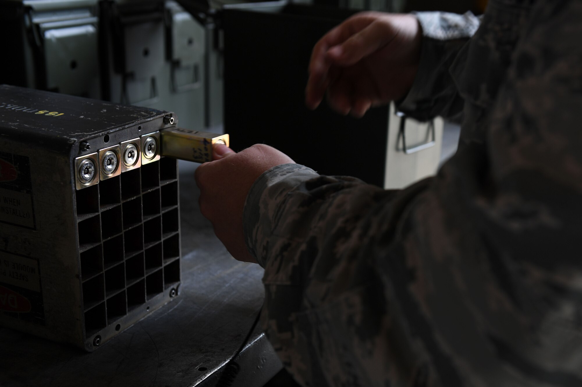 A hand pushes a flare into its rectangular compartment amongst other flares.