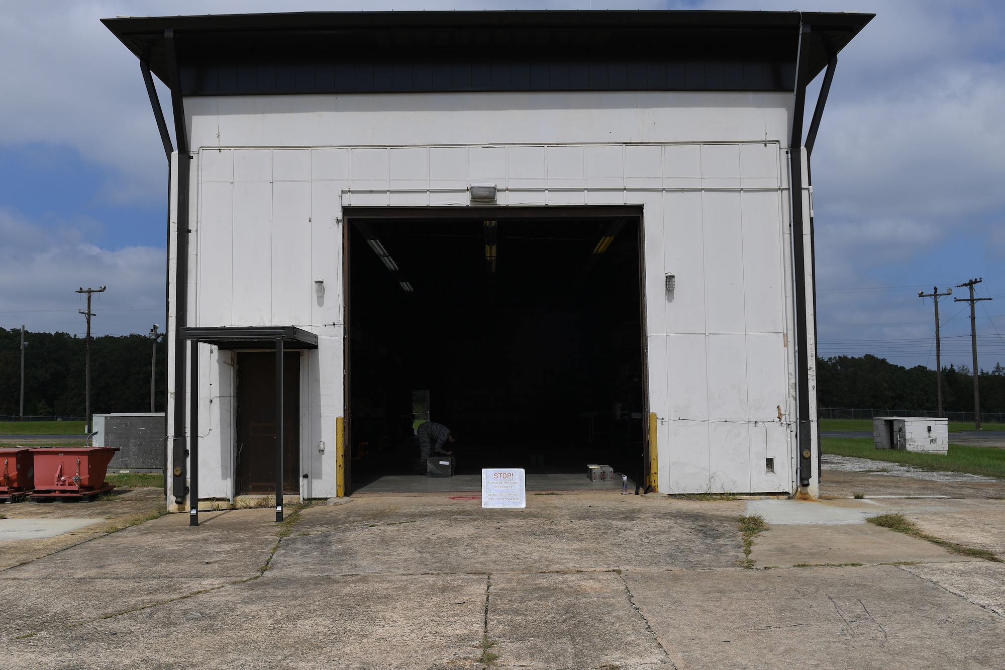 A woman bends over in a large entryway to a building to put a box down.