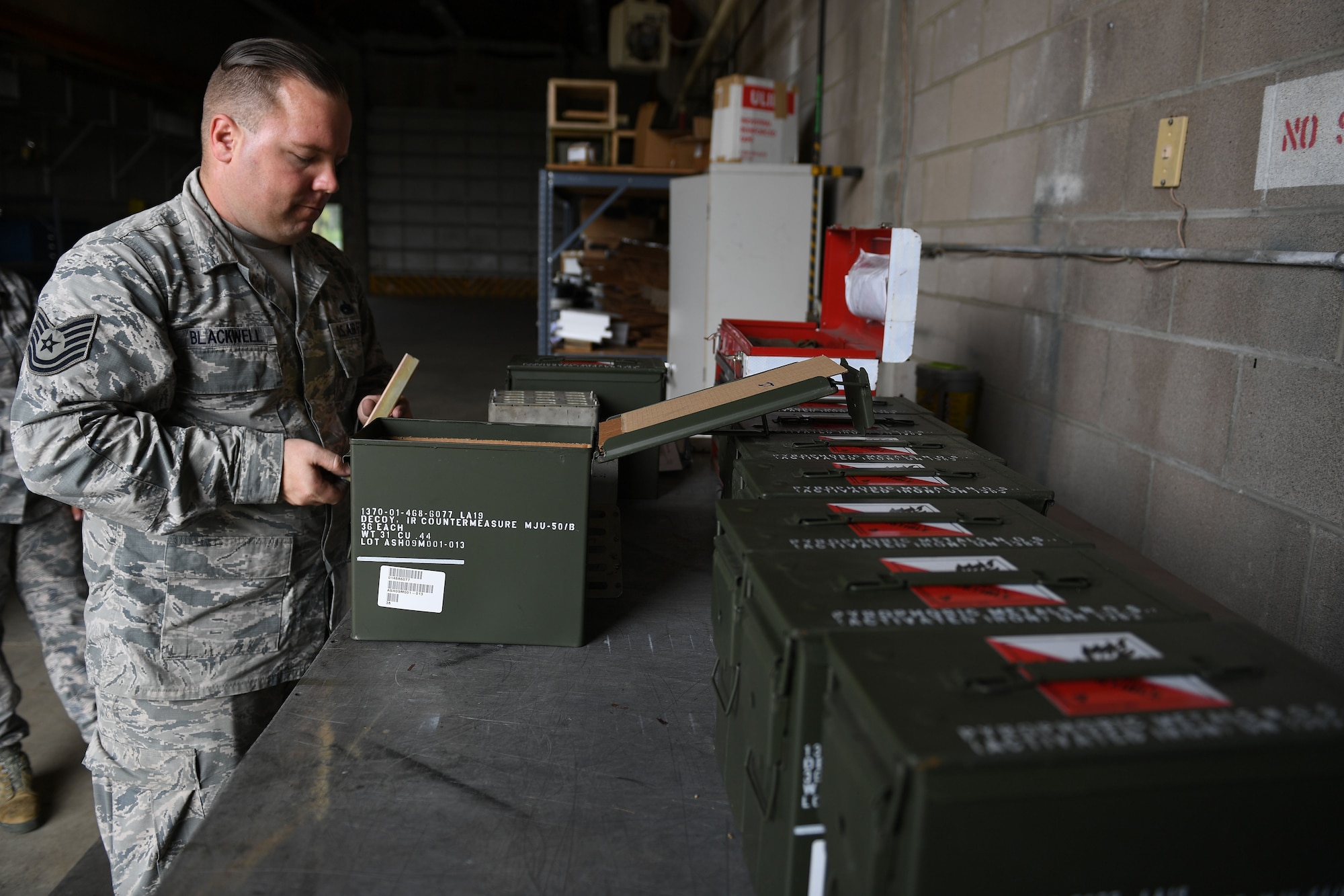 A man stands in front of a table and opens a container.