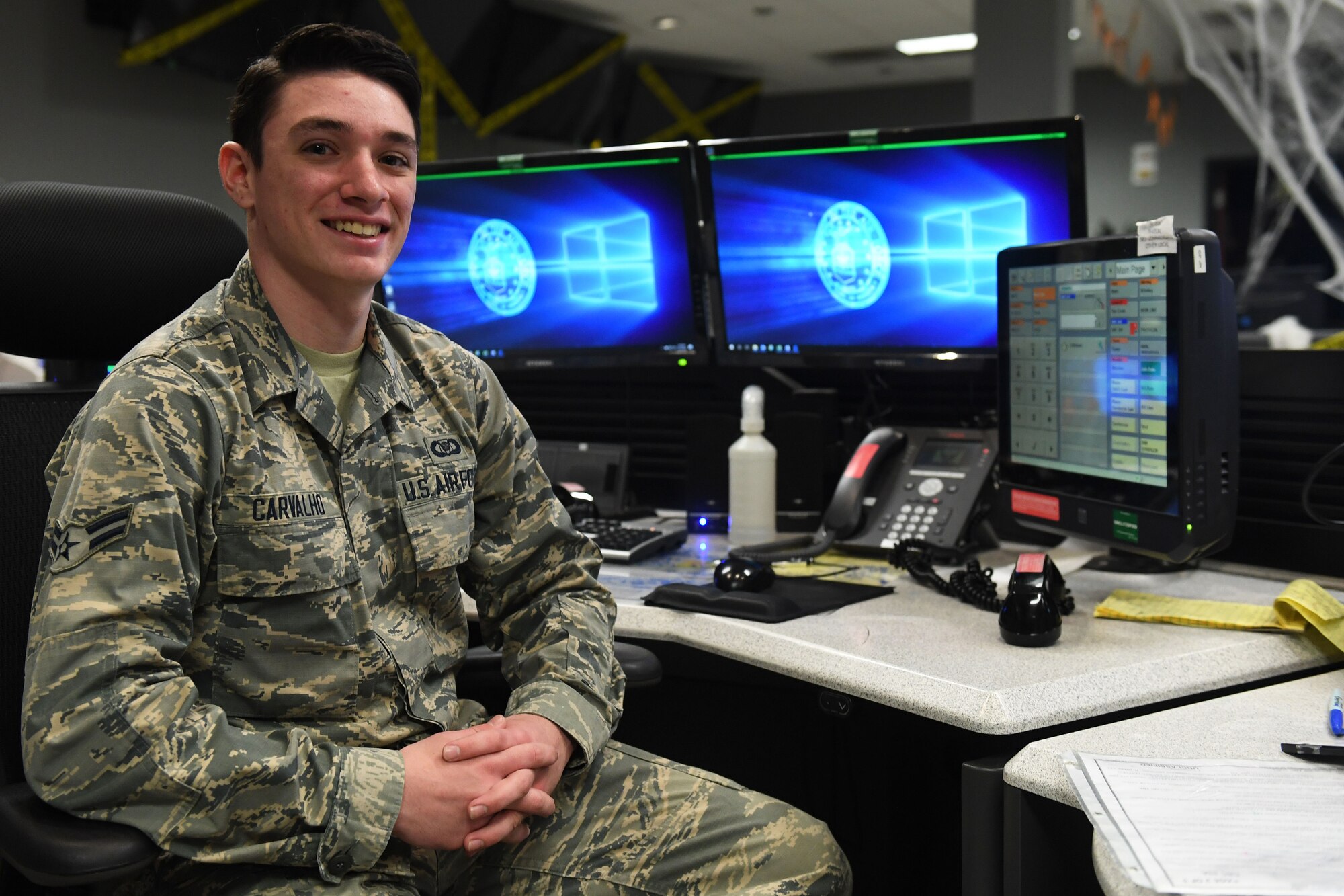 A man sits at a desk and smiles.