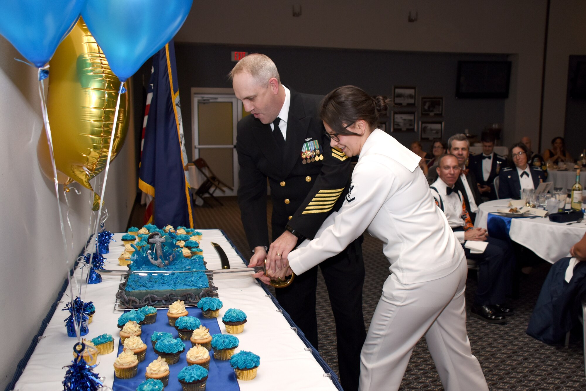 U.S. Navy Senior Chief Petty Officer Micah Epley, Navy Center for Information and Warfare Training Detachment Goodfellow senior enlisted leader, and Petty Officer 3rd Class Ashley Williamson, CIWT student, cut the birthday cake during the 243rd Navy Day Ball at the Event Center on Goodfellow Air Force Base, Texas, Oct. 12, 2018. Traditionally the cake is cut by the individual with the most years in service and the member with the least amount of years in service. (U.S. Air Force photo by Airman 1st Class Seraiah Hines/Released)