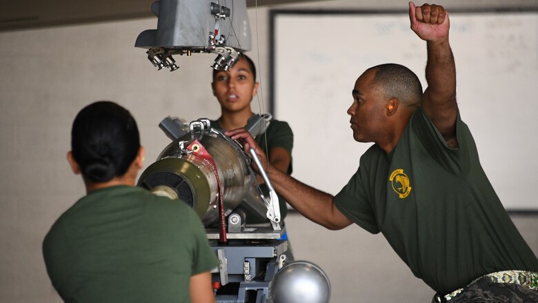 Airmen secure a GBU-12 bomb to the wing of an F-35A Lightning II during a weapons load competition at Hill Air Force Base, Utah