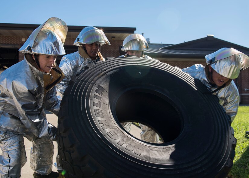 Members of the Chaplain and Friends team flip a tire during a Fire Prevention Week challenge at Joint Base Langley-Eustis, Virginia, Oct. 12, 2018.