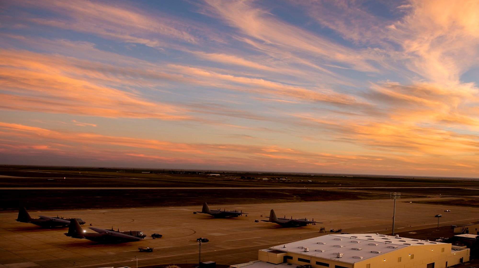 Planes sit on the Cannon Air Force Base flight line as the sun sets