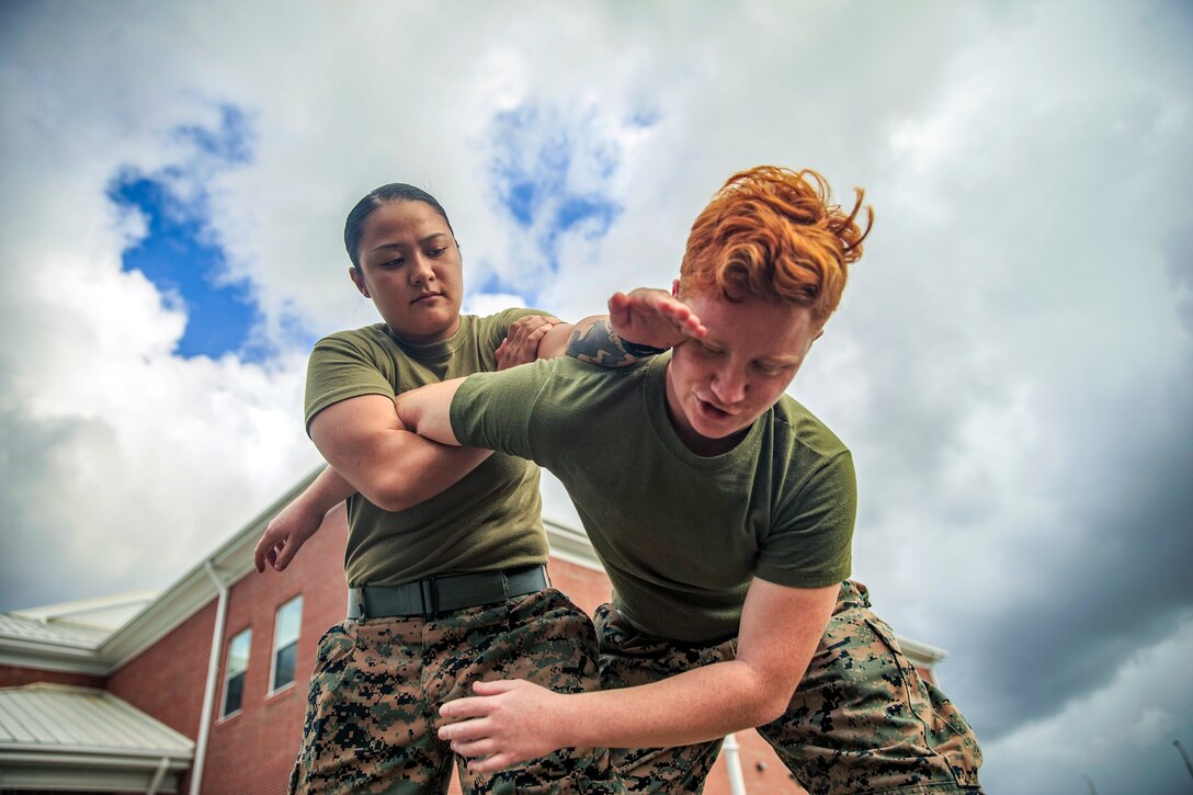 A Marine practices an arm-locking holding technique on another Marine.
