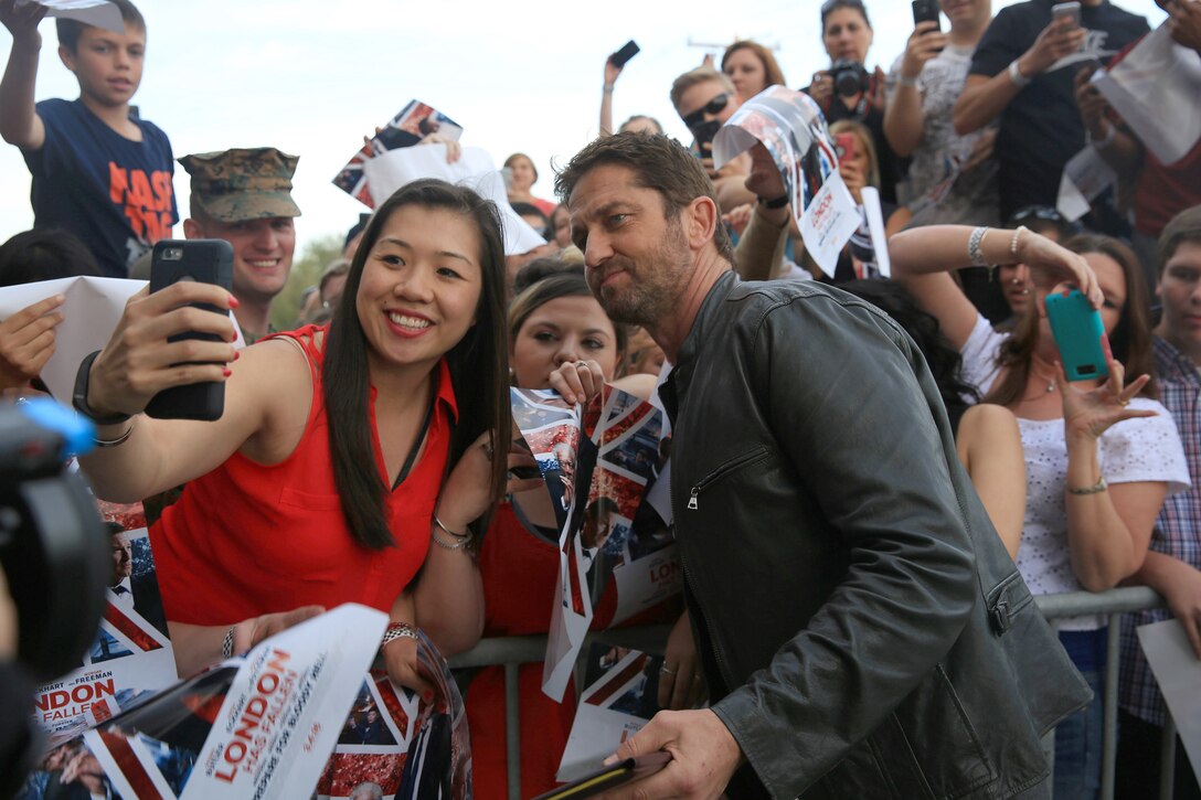 Movie star Gerard Butler takes a selfie with a woman.