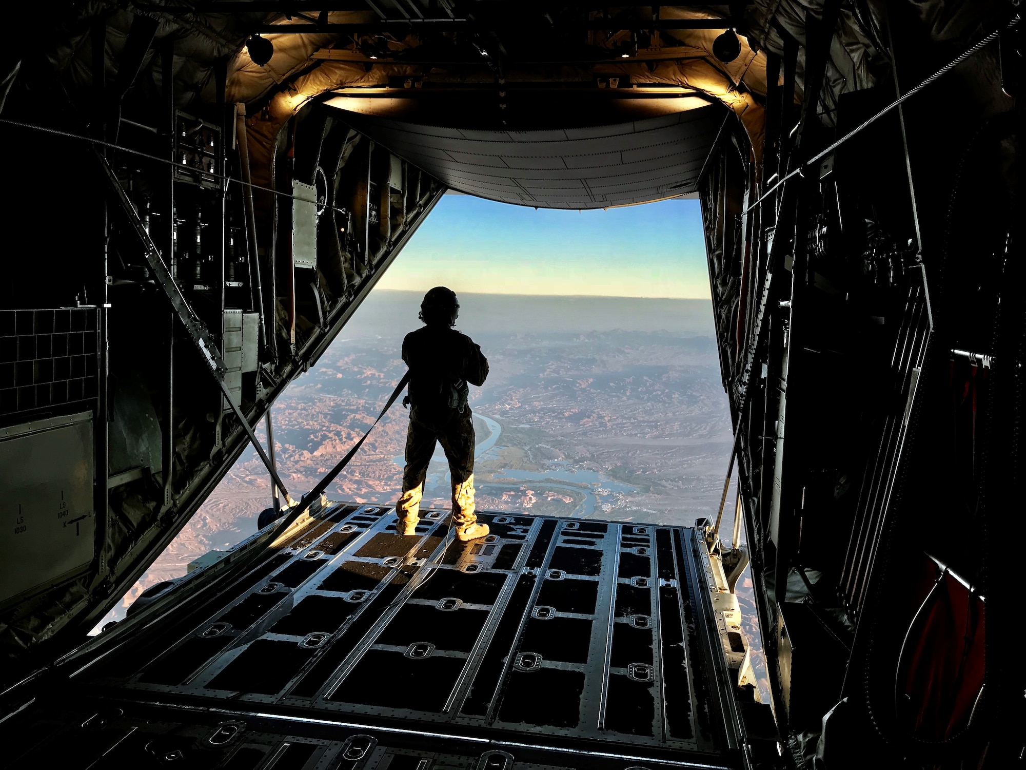 Senior Airman Christopher Godkin, 815th Airlift Squadron loadmaster, looks out the cargo door at 9,000 feet over Laguna Army Airfield at Yuma Army Proving Grounds, Yuma, Ariz during a combined training event with the Military Freefall School, Oct. 1-5, 2018.  The Air Force Reserve 815th AS provided airlift for the joint forces training school, which covers all aspects of military freefall parachuting. (U.S. Air Force photo by Master Sgt. Anthony Flores)