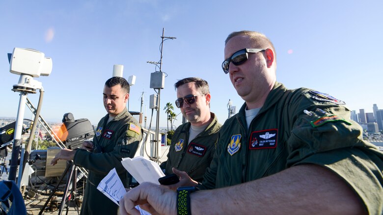 Tech Sgt. Robert Villa, Maj. Duncan Reed and Master Sgt. Caleb Patterson, all with 418th Flight Test Squadron, 412th Test Wing, conduct timeline checks in coordination with a C-17 Globemaster flight crew prior to the start of Game 3 of Major League Baseball’s National League Championship Series between the Los Angeles Dodgers and Milwaukee Brewers at Dodger Stadium in Los Angeles, California, Oct. 15. The C-17 flyover coincided with the opening ceremony of the game.  (U.S. Air Force photo by Giancarlo Casem)