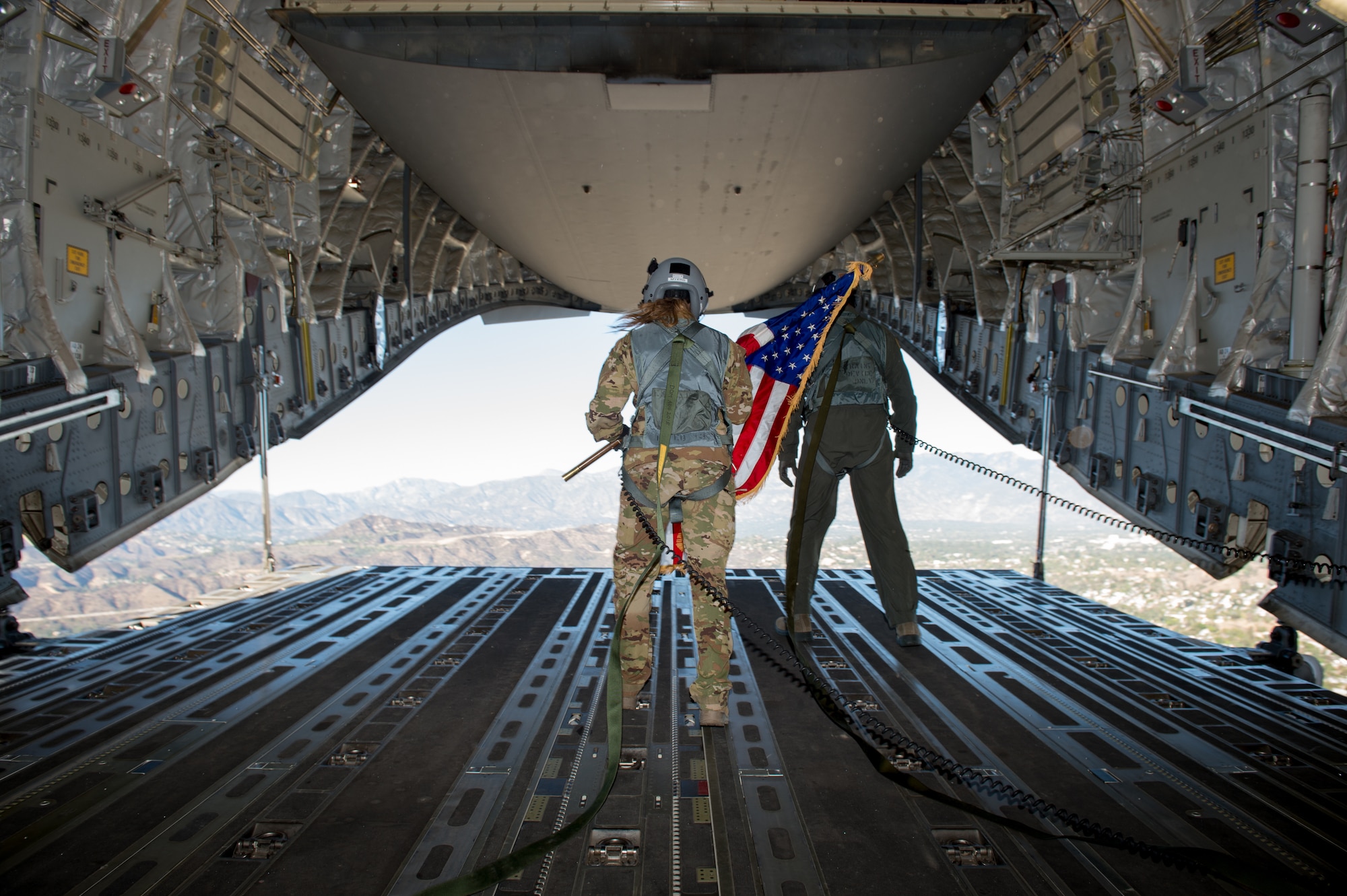 Staff Sgt. Kori Myers, 418th Flight Test Squadron load master, waves the American flag out of the back of a C-17 Globemaster III during the beginning of Game 3 of the National League Championship Series between the L.A. Dodgers and Milwaukee Brewers. The 412th Test Wing at Edwards Air Force Base, California, provided the C-17 for the ceremonial flyover. (U.S. Air Force photo by Kyle Larson)