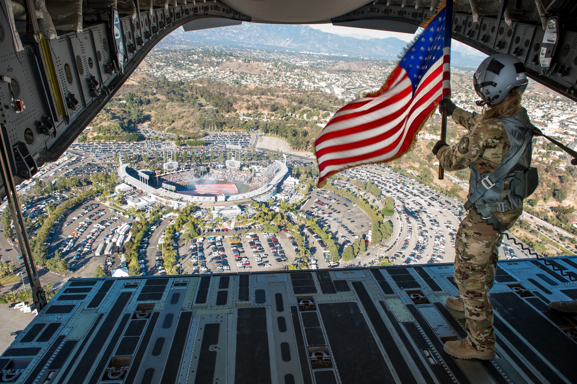 Staff Sgt. Kori Myers, 418th Flight Test Squadron load master, waves the American flag out of the back of a C-17 Globemaster III during the beginning of Game 3 of the National League Championship Series between the L.A. Dodgers and Milwaukee Brewers. The 412th Test Wing at Edwards Air Force Base, California, provided the C-17 for the ceremonial flyover. (U.S. Air Force photo by Kyle Larson)