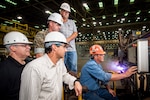 Paul Bosarge, burner workleaderman, starts fabrication on Bougainville (LHA 8) with others observing, from left, Frank Jermyn, LHA 8 ship program manager; Lance Carnahan, Steel Fabrication director; Marine Corps Capt. J.D. Owens, representing SUPSHIP, Gulf Coast; and Ricky Hathorn, Hull general superintendent.