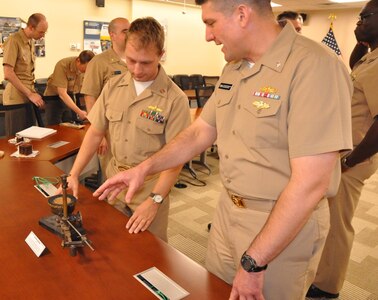 IMAGE: DAHLGREN, Va. (Oct. 12, 2018) - Cmdr. Steven Perchalski, right, and Lt. Adam Mattison examine a World War I bombsight - used to conduct testing at the Dahlgren Naval Proving Ground in the 1920s and 1930s - during a celebration of the Navy's 243rd birthday held at the Naval Surface Warfare Center Dahlgren Division (NSWCDD). The aircraft course-setting bombsight is one of the few surviving examples of the many bombsights tested at Dahlgren. NSWCDD will celebrate 100 years of cutting-edge technological innovation in support of the warfighter at a centennial grand finale event Oct. 19 that includes an exhibition tent, a U.S. Navy Band performance, and historic tours featuring six station stops on base.