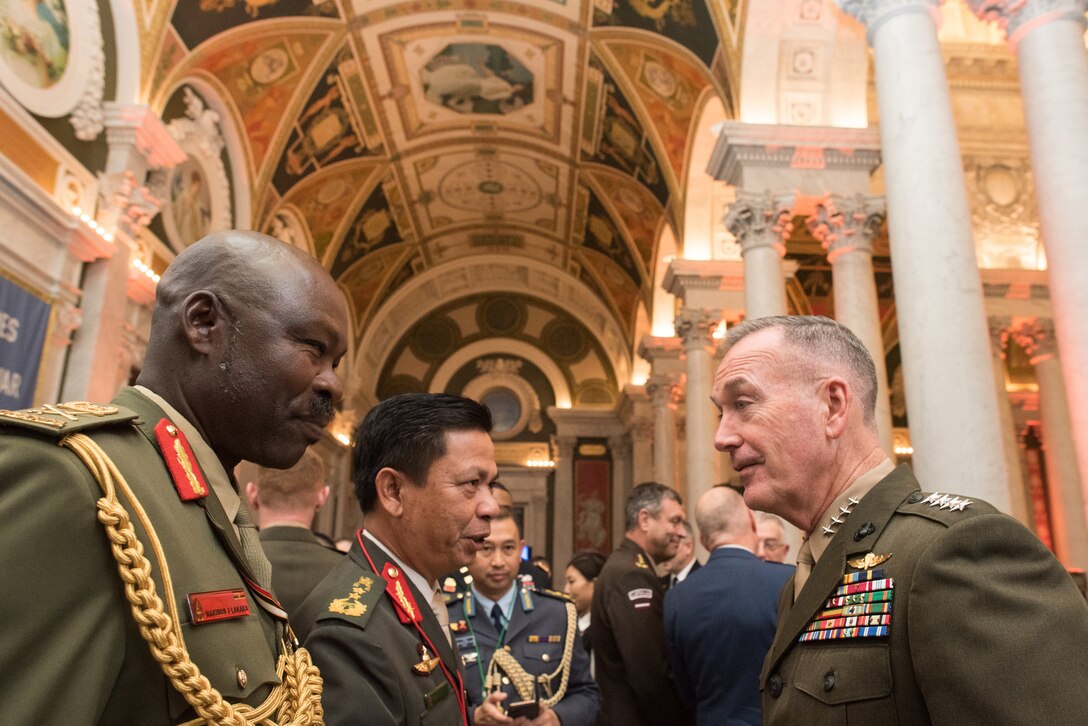 Marine Corps Gen. Joe Dunford talks with two foreign military officials in a high-ceilinged room with pillars.