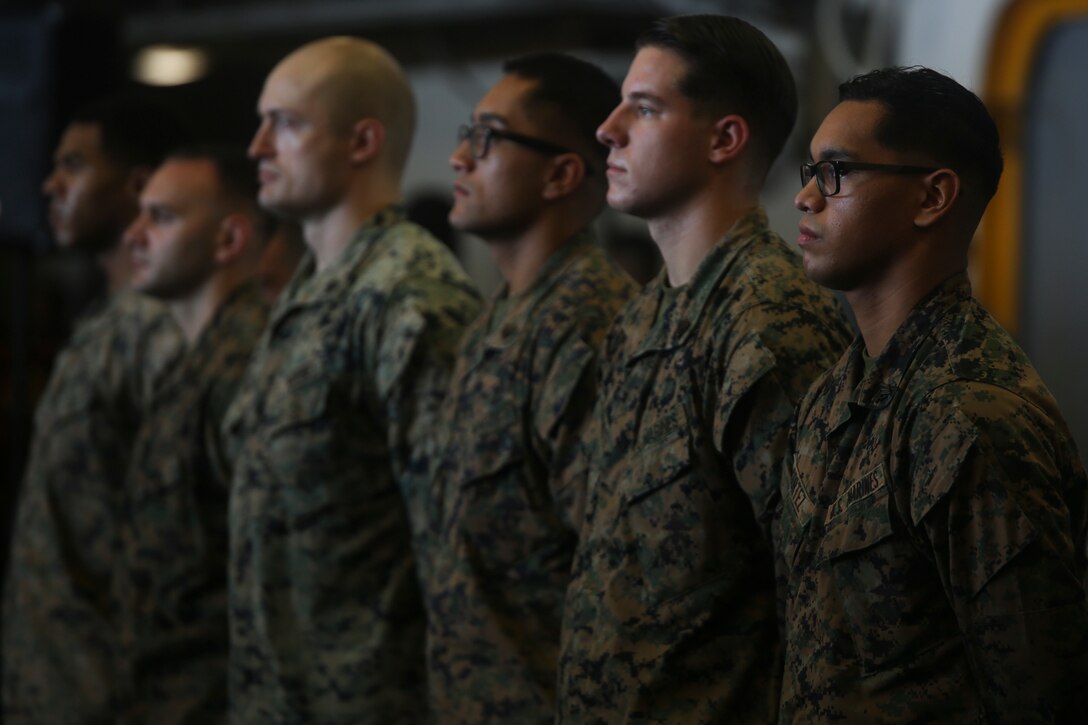 Faculty advisors with the 31st Marine Expeditionary Unit stand at attention for the Marines’ Hymn during a corporal’s course graduation aboard the amphibious assault ship USS Wasp (LHD 1), underway in the South China Sea, Sept. 27, 2018. Corporal’s course, usually a three-week course, is condensed to two weeks while underway. The course helps Marine leaders/Noncommissioned Officers refine their understanding of small unit leadership principles.The 31st MEU, the Marine Corps’ only continuously forward-deployed MEU, provides a flexible force ready to perform a wide-range of military operations. (U.S. Marine Corps photo by Lance Cpl. Hannah Hall/Released)