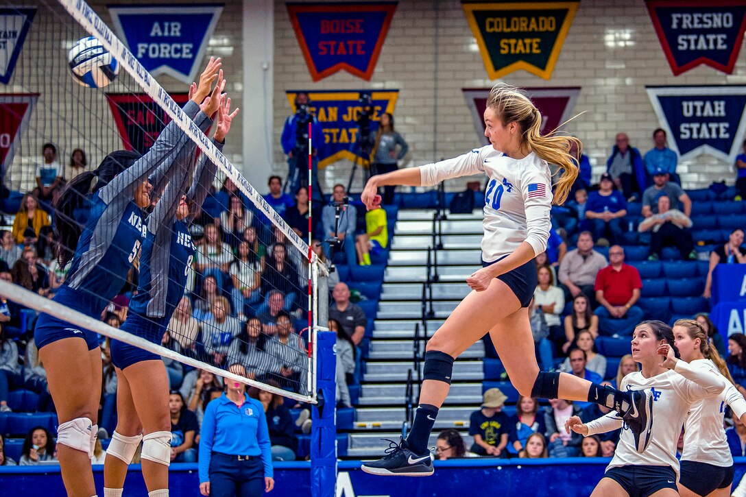 An Air Force cadet spikes a volleyball at the net.