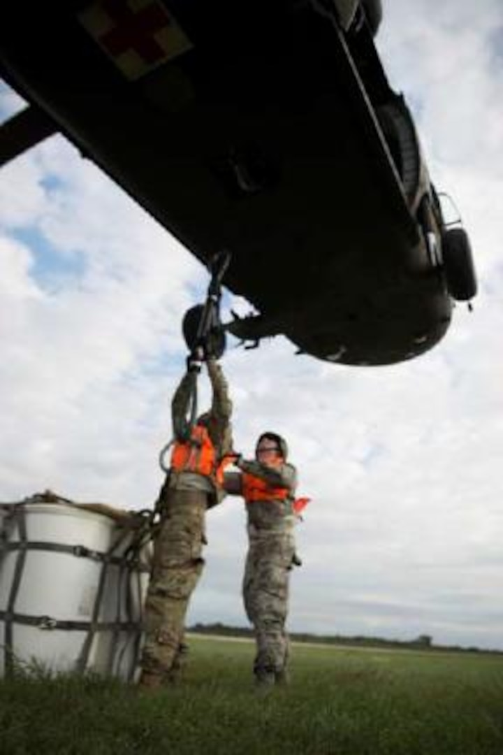 2nd Lt. Brandon Smolinski (right) prepares to brace Capt. Nathan Del Rio against the rotor wash of a UH-60 Black Hawk helicopter