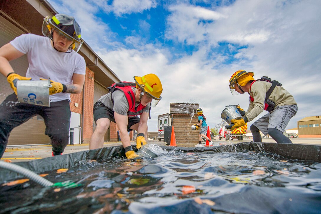 Airmen fill buckets in a water trough.