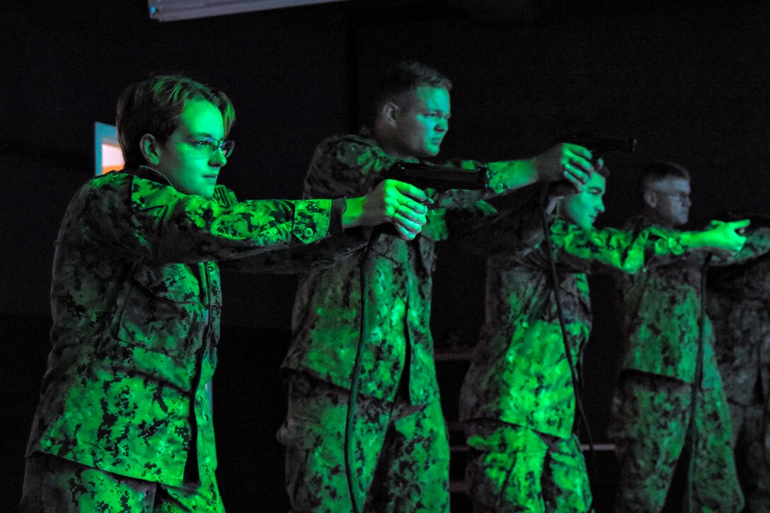 Four sailors in a line aim down pistol sights.