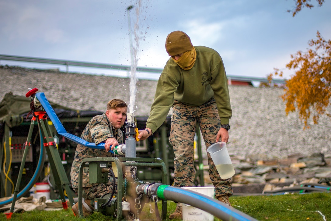 Two Marines release air from a hose.