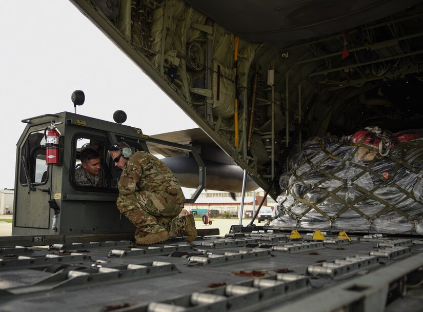 U.S. Air Force Airman First Class Jaxson Doyle, 733rd Logistics Readiness Squadron small air terminal representative, speaks with Airman First Class Jack Faught, 71st Rescue Squadron loadmaster, after gear and supplies heading to Tyndall Air Force Base, Florida, are loaded onto a HC-130J Combat King II at Joint Base Langley-Eustis, Virginia, Oct. 17,2018. The 71st RQS and HC-130J Combat King II are from Moody Air Force Base, Georgia. (U.S. Air Force photo by Staff Sgt. Carlin Leslie/Released)