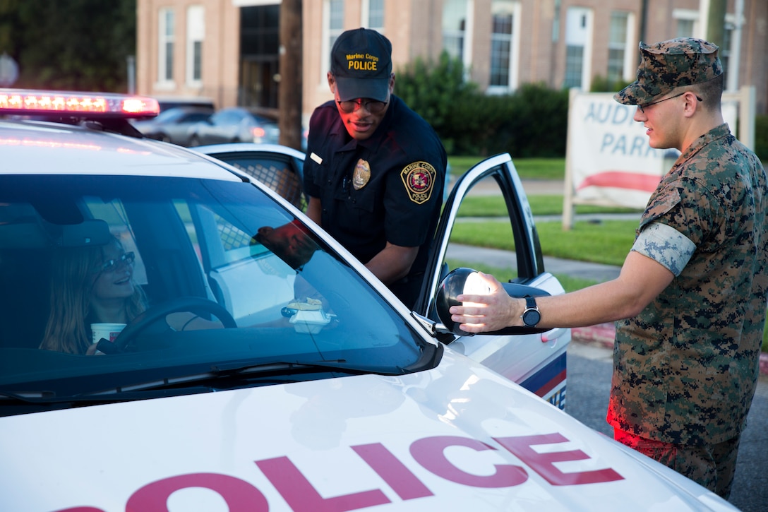Cpl. Jacob D. Edwards, a military police officer with Marine Corps Support Facility New Orleans, shows children how his patrol car works car during the annual “Night Out Against Crime” held at the Village at Federal City, New Orleans, Oct. 16, 2018. “Night Out Against Crime” is a yearly event in which Marines, officers within the New Orleans Police Department and other first responders come together with community members to raise awareness of police officer presence. (U.S. Marine Corps photo by Sgt. Melissa Martens)