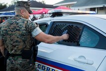 Lance Cpl. Patrick J. Clavin, a military police officer with Marine Corps Support Facility New Orleans, lets children explore his patrol car during the annual “Night Out Against Crime” held at the Village at Federal City, New Orleans, Oct. 16, 2018. “Night Out Against Crime” is a yearly event in which Marines, officers within the New Orleans Police Department and other first responders come together with community members to raise awareness of police officer presence. (U.S. Marine Corps photo by Sgt. Melissa Martens)