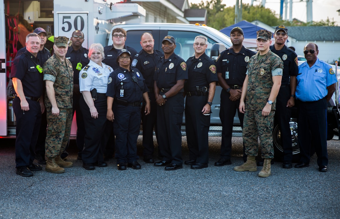 Marines, police officers with Marine Corps Support Facility New Orleans, and local first responders pose for a photo during the annual “Night Out Against Crime” held at the Village at Federal City, New Orleans, Oct. 16, 2018.  “Night Out Against Crime” is a yearly event in which Marines, officers within the New Orleans Police Department and other first responders come together with community members to raise awareness of police officer presence. (U.S. Marine Corps photo by Sgt. Melissa Martens)