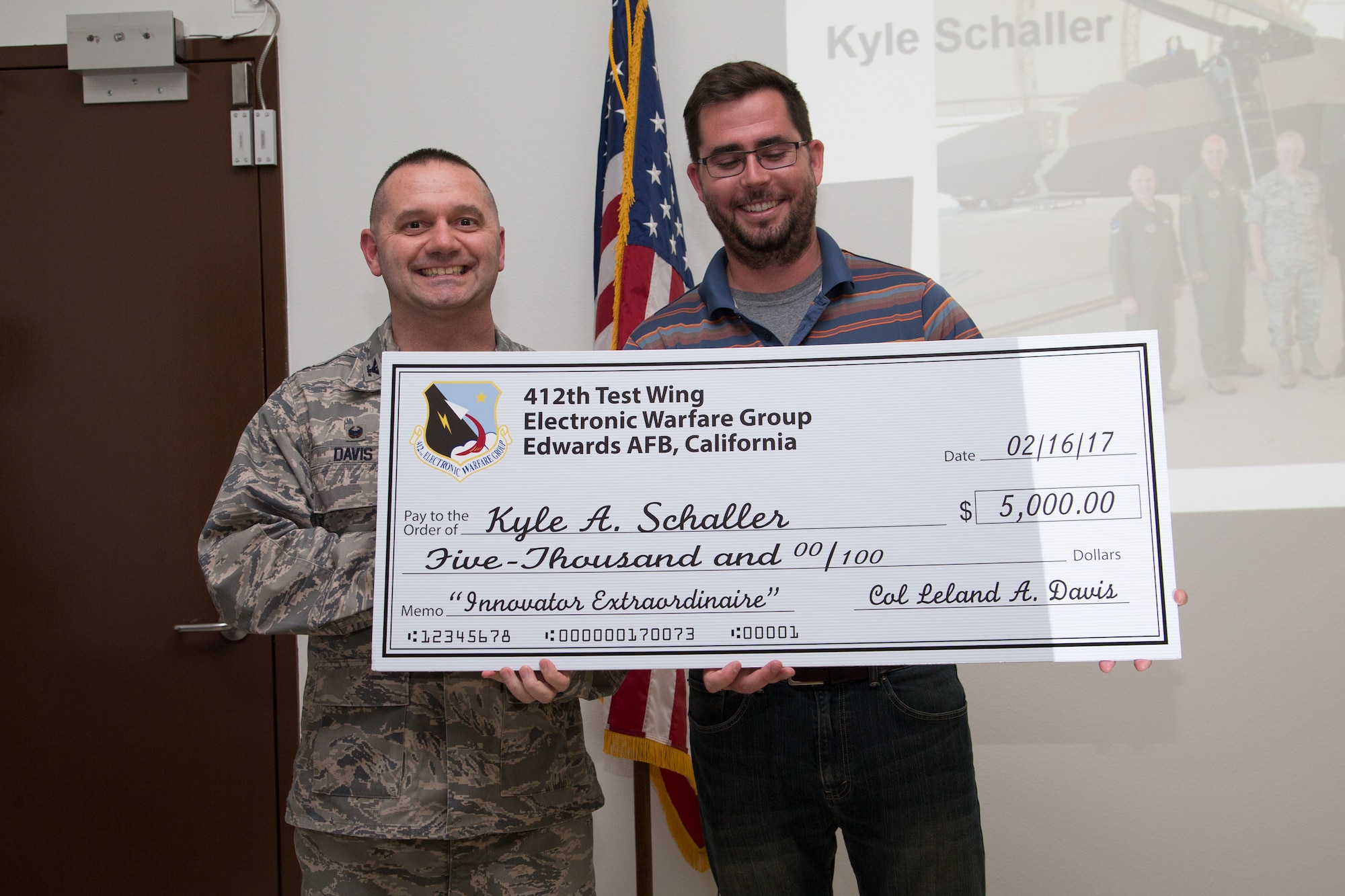 Former 412th Electronic Warfare Group commander Col. Leland Davis poses for a photo with Kyle Schaller, 771st Test Squadron, and a large check Schaller received for an innovative idea. (Air Force photo by Donald R. Allen)