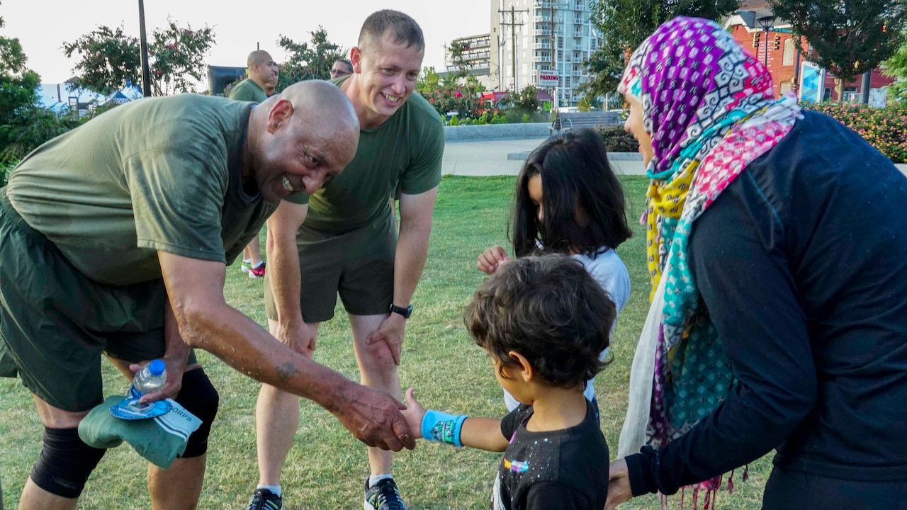 Retired Marine shakes child’s hand.