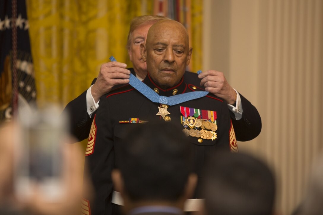 President Donald J. Trump places a medal around the neck of a Marine.