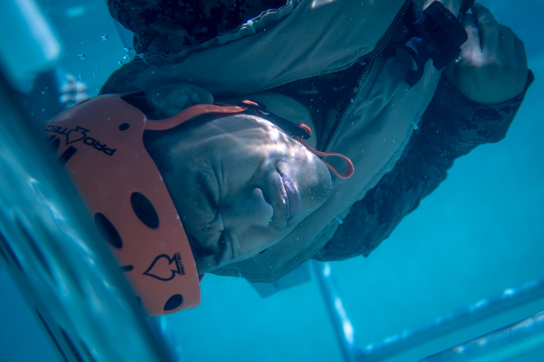 A Marine with the 11th Marine Expeditionary Unit is flipped upside-down in a shallow water egress trainer at Camp Pendleton, California, Oct. 12, 2018. The SWET prepares Marines to train in the Modular Amphibious Egress Trainer, a simulated sinking aircraft, and is a requirement for all Marines that will deploy with the 11th MEU.