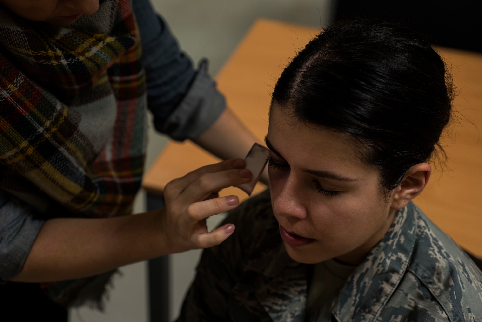 Heather Biechler, 52nd Medical Operations Squadron family advocacy counselor, left, applies moulage makeup to U.S. Air Force Senior Airman Miranda Gollnick, 52nd Logistic Readiness Squadron material management technician, right, at Spangdahlem Air Base, Germany, Oct. 17, 2018. Gollnick volunteered to wear the makeup for one day as part of the Black Eye Campaign, a domestic violence awareness social experiment. The event was designed to see how people respond to signs of domestic violence. (U.S. Air Force photo by Airman 1st Class Valerie Seelye)