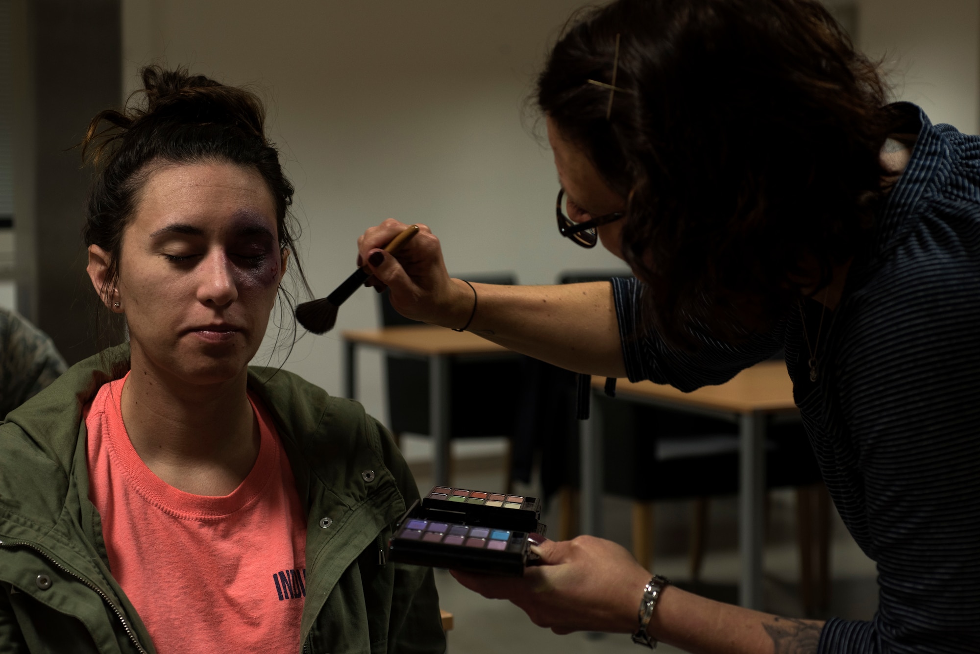 Connie Kurtze, 52nd Medical Operations Squadron family advocacy program assistant, right, applies moulage makeup to U.S. Air Force Staff Sgt. Ashley Payne, 726th Air Mobility Squadron command support staff NCO in-charge, left, at Spangdahlem Air Base, Germany, Oct. 17, 2018. Payne wore the simulated injury for one day in support of the Black Eye Campaign, a social experiment to raise domestic violence awareness. Each volunteer tracked how people responded to their appearance. (U.S. Air Force photo by Airman 1st Class Valerie Seelye)