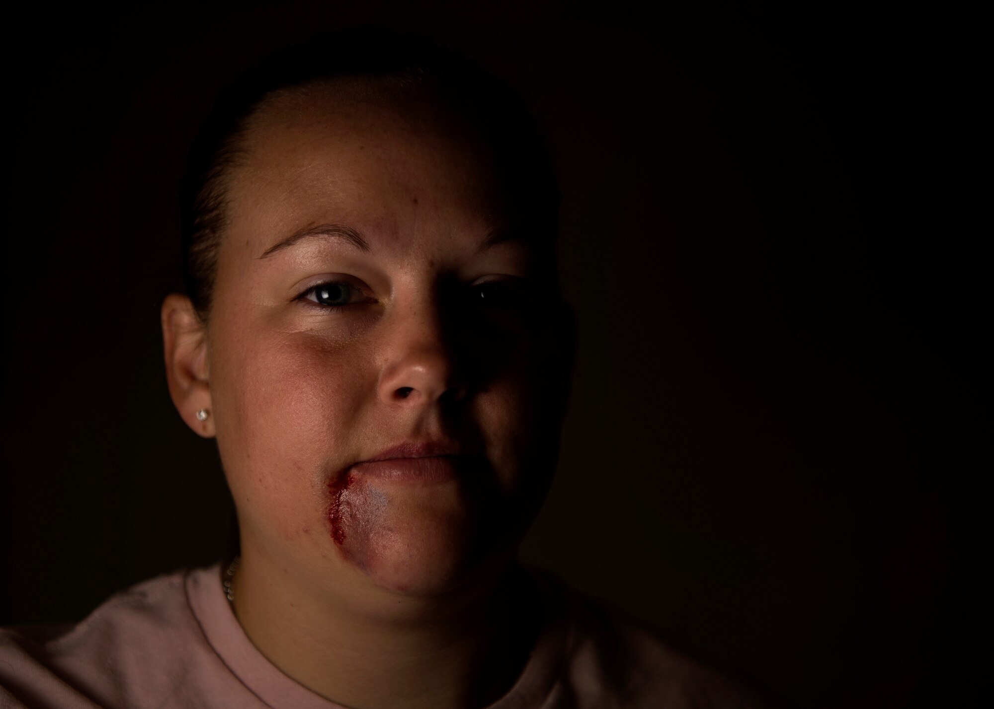 U.S. Staff Sgt. Andrea Sall, 726th Air Mobility Squadron passenger service supervisor, poses for a portrait while wearing moulage makeup at Spangdahlem Air Base, Germany, Oct. 17, 2018. Sall volunteered to simulate a victim of domestic violence for one day in support of the Black Eye Campaign. The social experiment was held to raise awareness within the community of the importance of recognizing and responding to domestic violence. (U.S. Air Force photo by Airman 1st Class Valerie Seelye)
